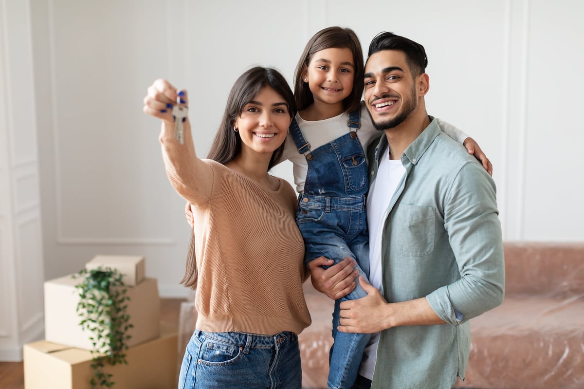 Young family holding a key to their new home while moving in