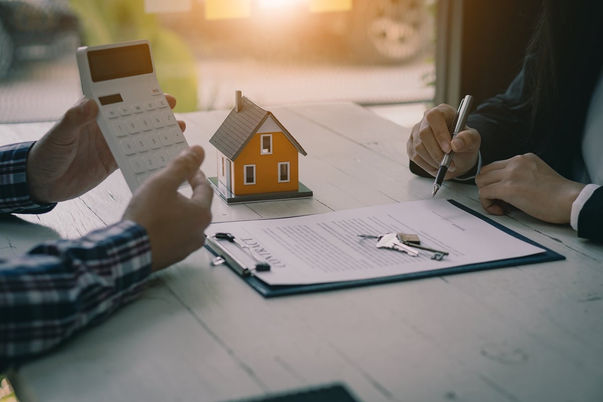 Real estate professionals offering contracts to clients to discuss home purchases or real estate loans in an office
