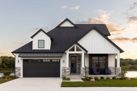 A black and white luxury home with a two car garage and professional landscaping at sunset
