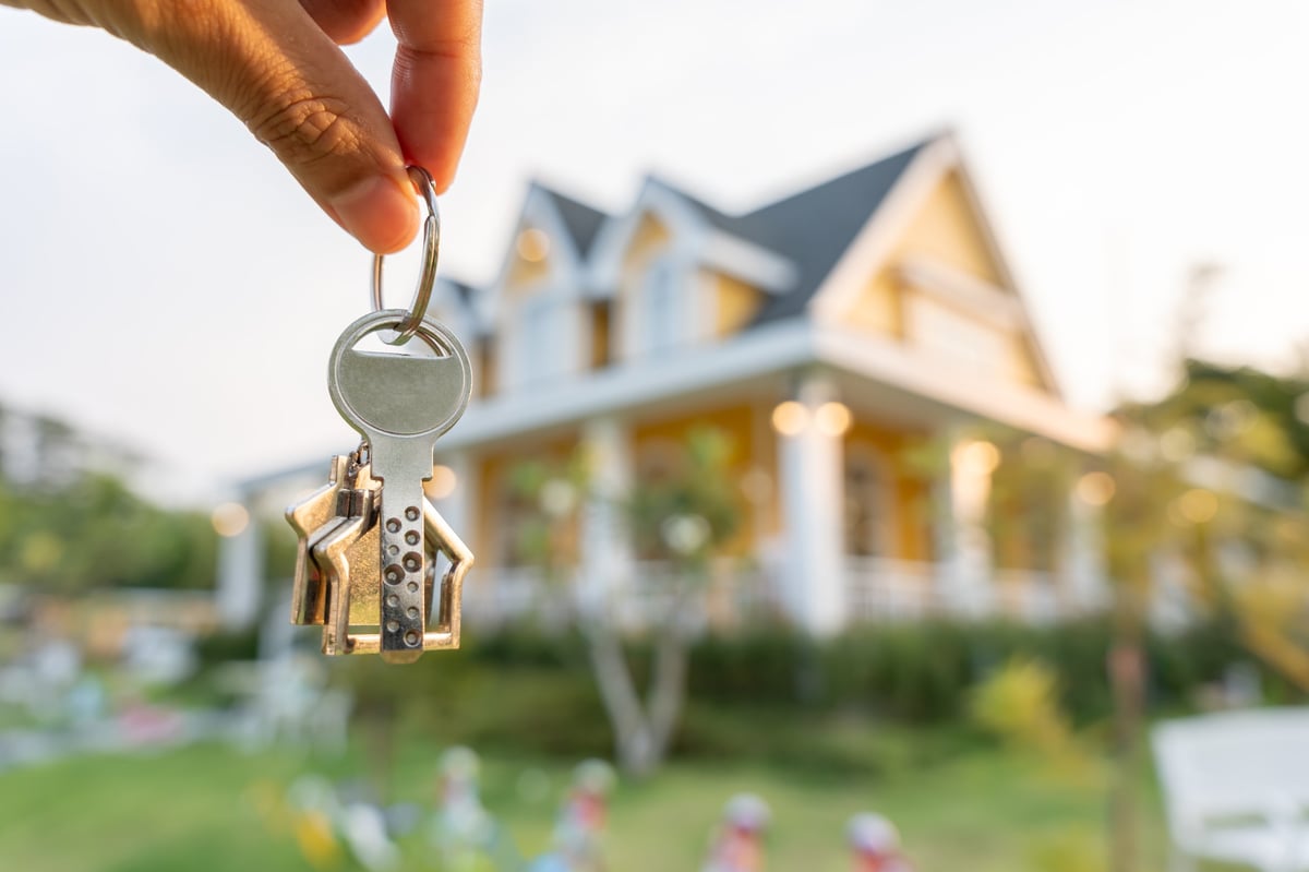 Real estate agent manager smiling and holding a key for a new owner.