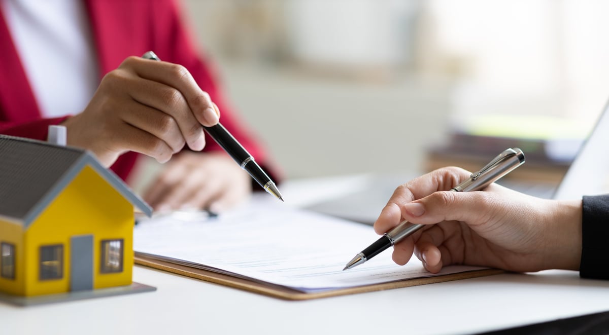 Businesswoman discusses with real estate agent, negotiates and signs contract for purchase of house and land