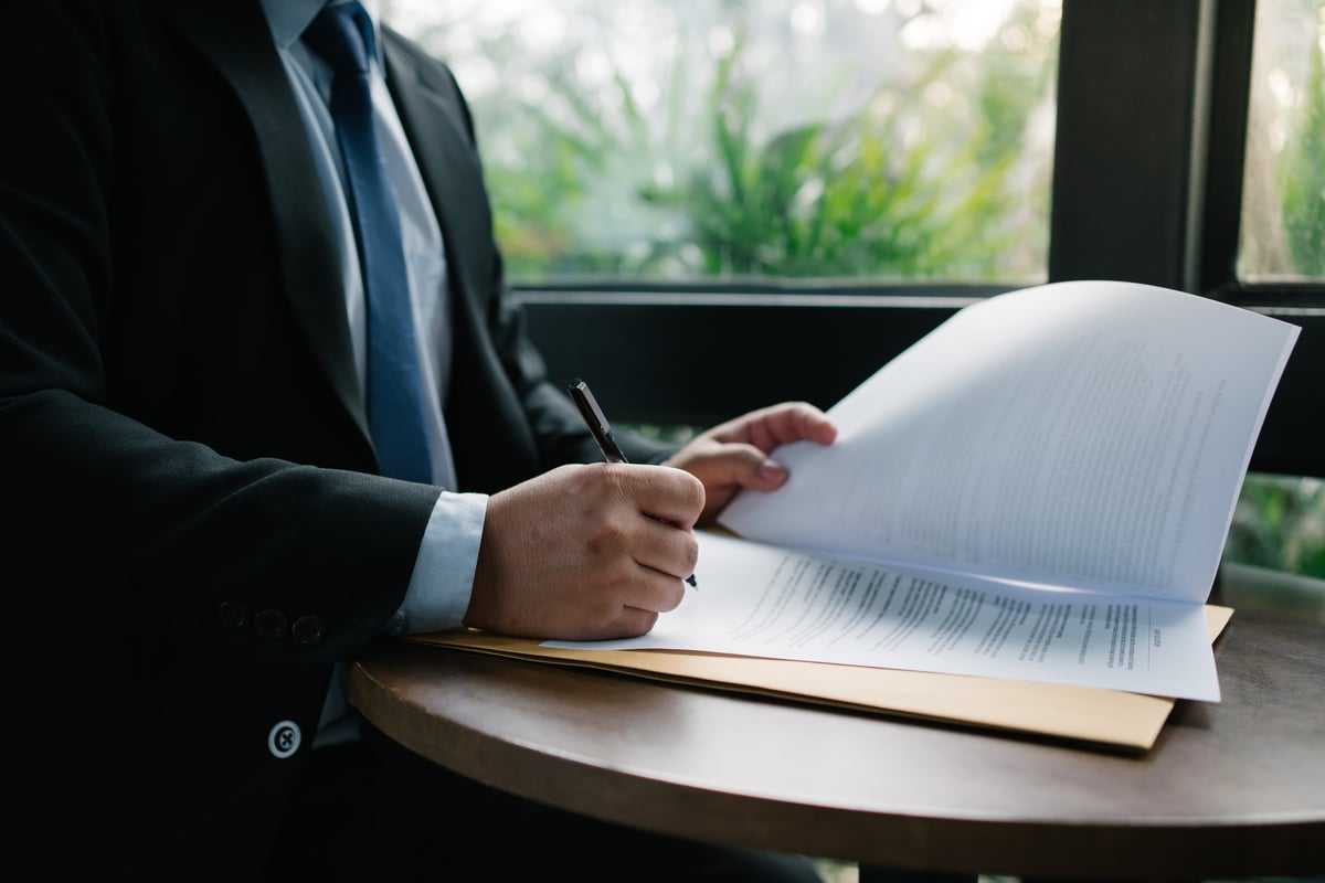 Businessman signing a document on a round table, showcasing legal agreement and professional commitment