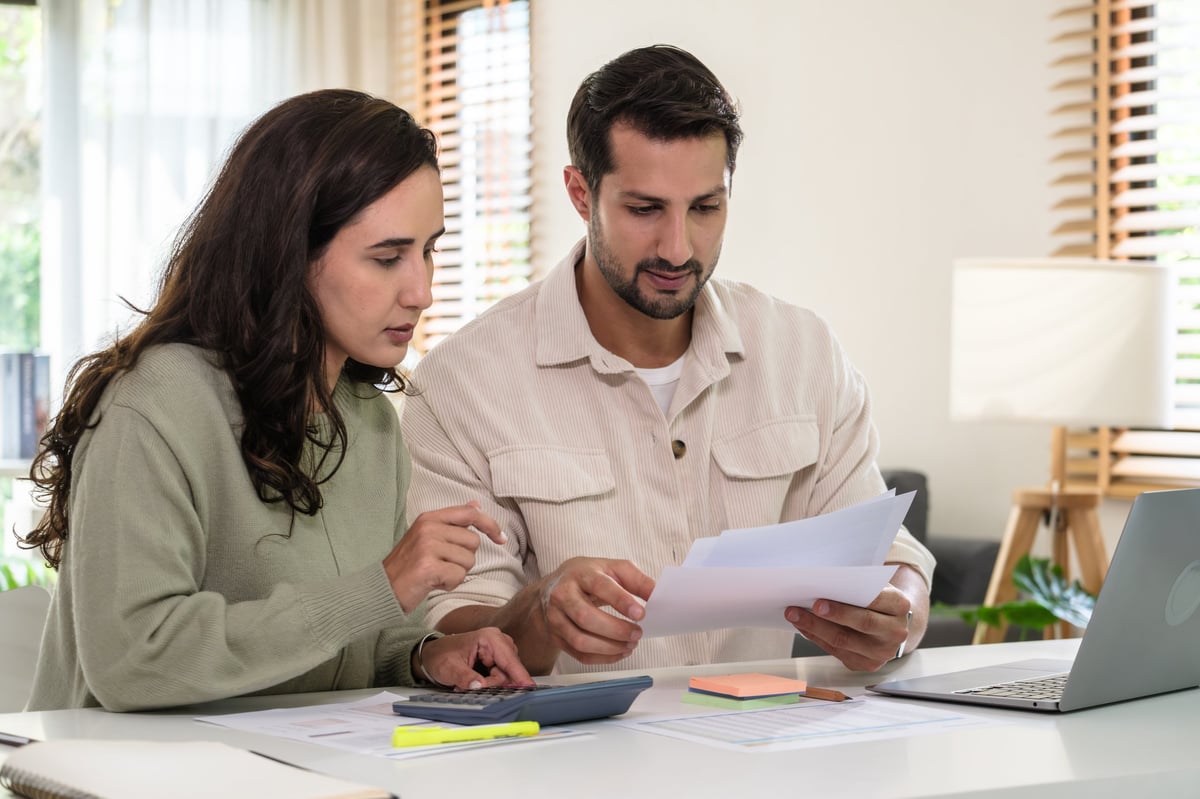 Couple reviewing their finances and tax documents on a laptop at home
