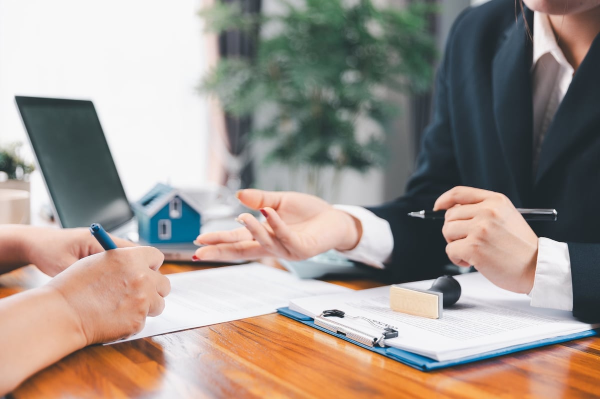 Advisor explaining loan terms and purchase agreement to a buyer signing documents
