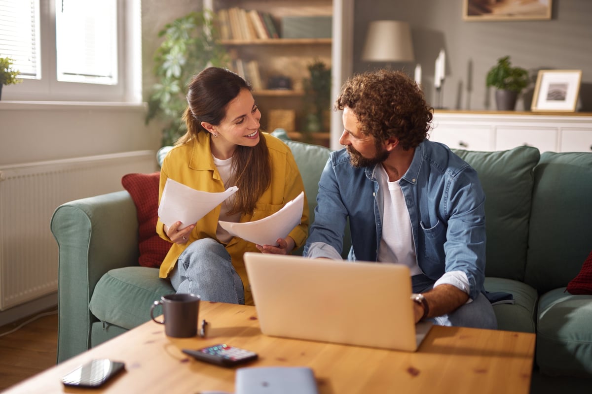 Young couple reviewing their finances and managing a household budget using a laptop at home