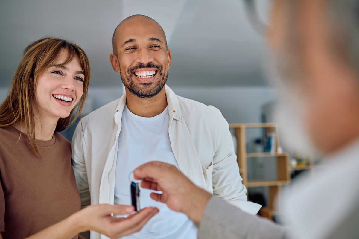 real estate agent handing over house keys to joyful homeowners, celebrating the successful closing of their real estate deal and new journey ahead