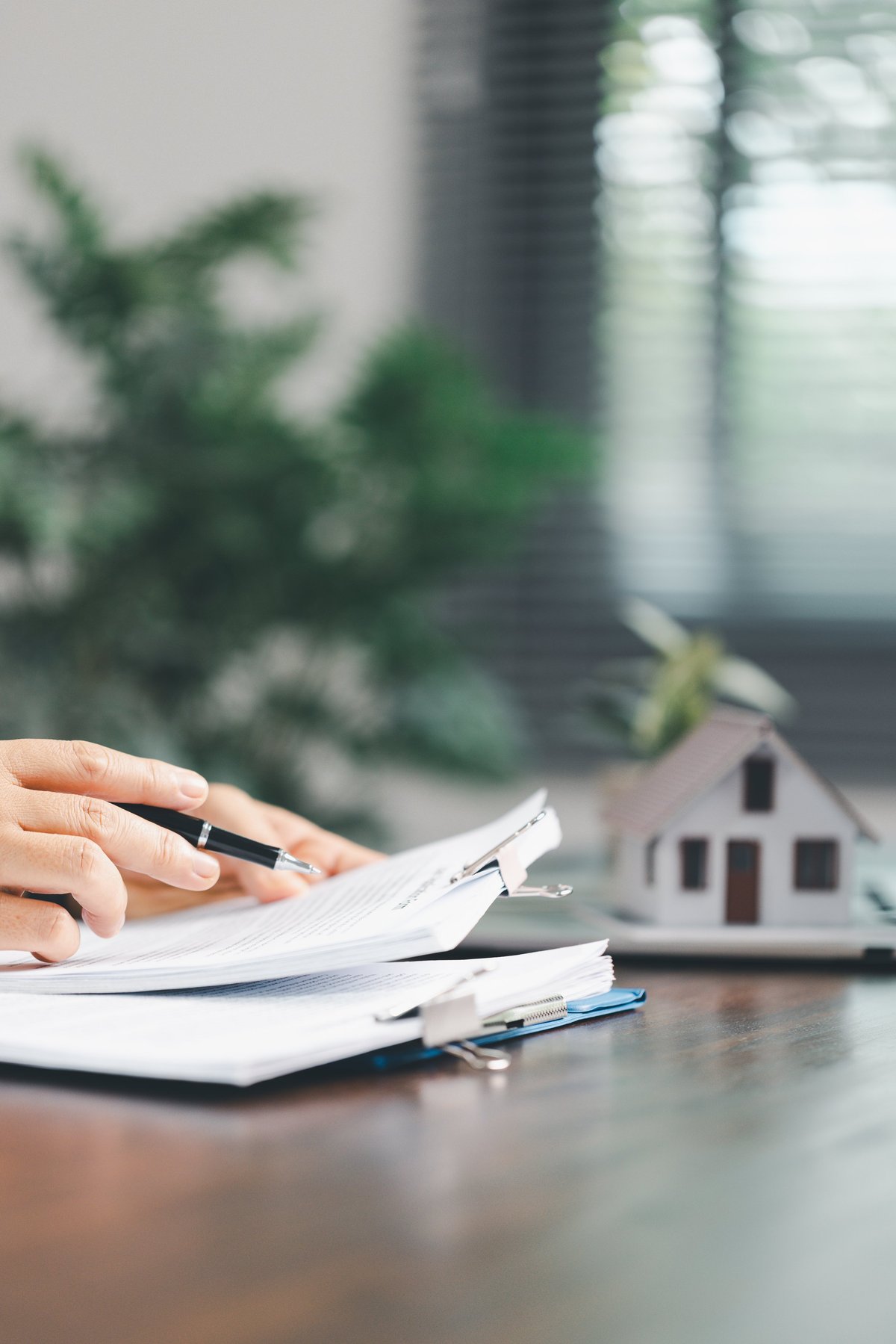 Real estate agent and client discussing a rental property purchase contract with a house model on the table