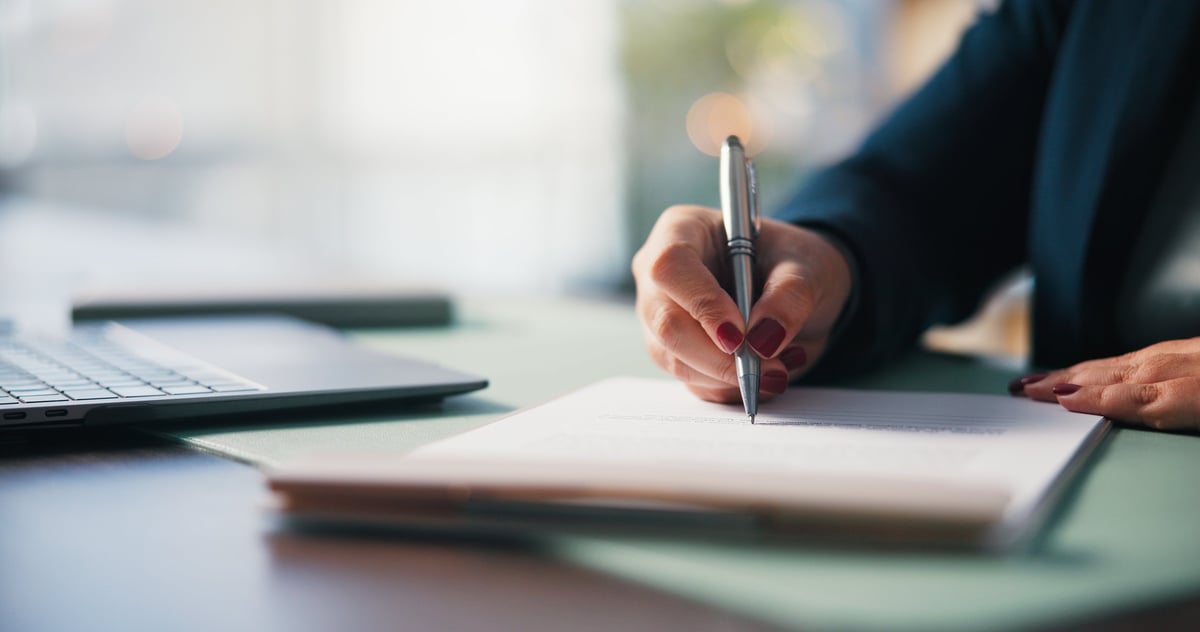 Hands signing a financial agreement across a desk