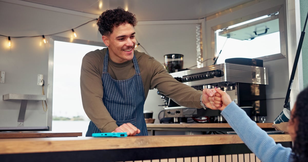 Fist bump, sale and smile with man in food truck for service or small business startup success