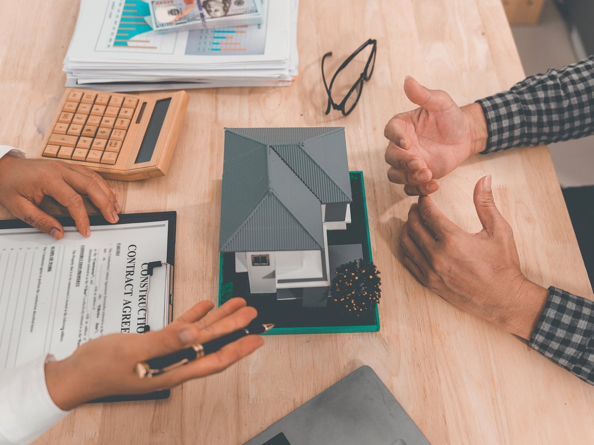 Mortgage agent explaining a home loan agreement and pointing to a document for a homeowner to sign