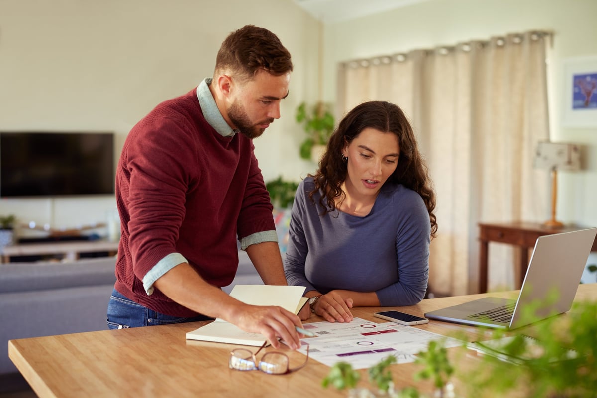 Mid adult couple working together at home with financial documents and bills using laptop