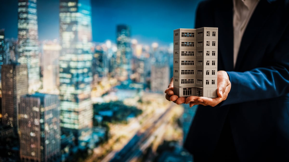 Business woman presenting detailed building model against vibrant city skyline, property development, investment stability, rental income potential, increasing value of immovable properties.