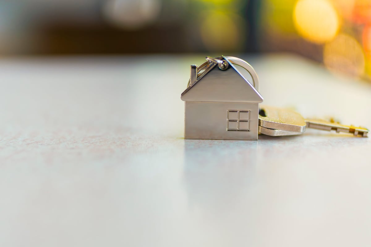 Keys and a model house on a table representing real estate investment