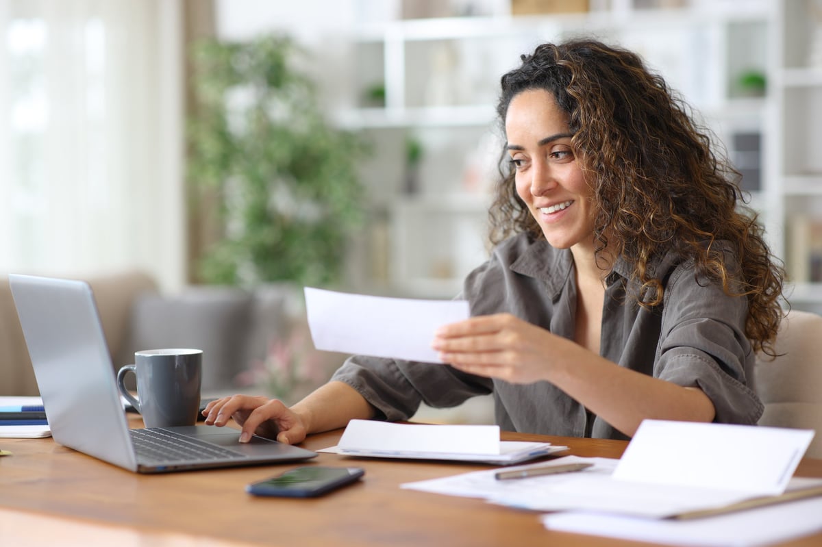 Happy freelancer checking bills and doing online accounting with a laptop working at home