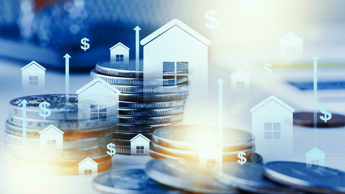 Stacks of coins with house icons rising above them show investment growth in real estate.