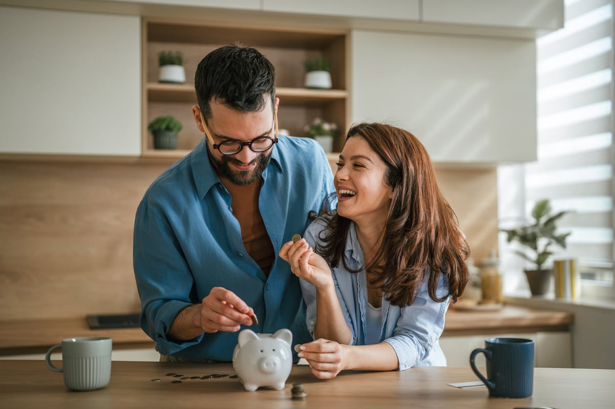 Young happy couple saving money together in a piggy bank, planning their financial future, investing in shared goals, and managing finances with a sense of security and domestic harmony