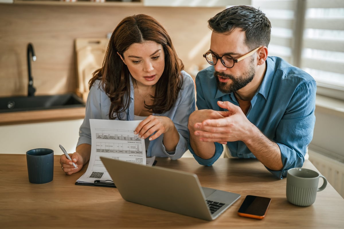 Young couple reviewing household finances and mortgage documents together at a modern kitchen table