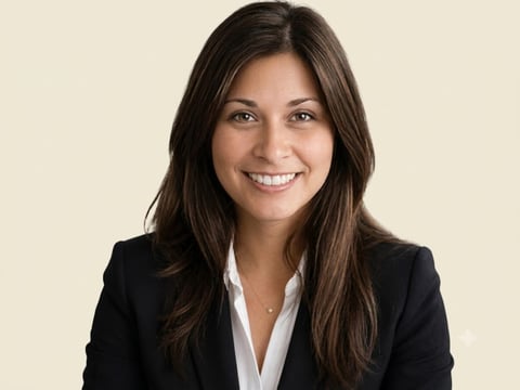Professional headshot of a smiling woman with long dark hair wearing a black blazer and white shirt
