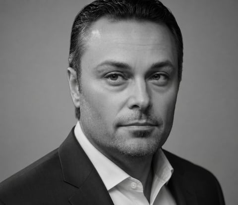 Black and white portrait of a man in a dark suit and white dress shirt against a neutral background