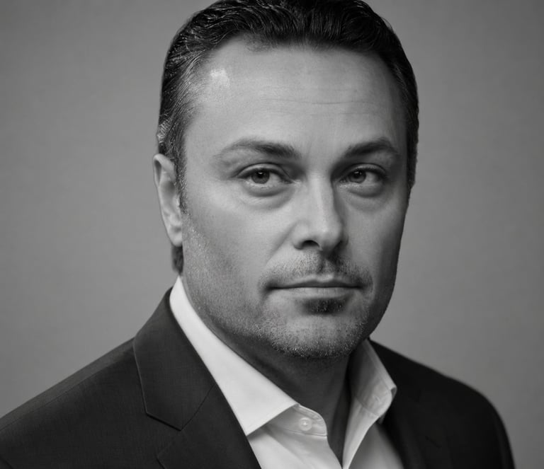 Black and white portrait of a man in a dark suit and white dress shirt against a neutral background