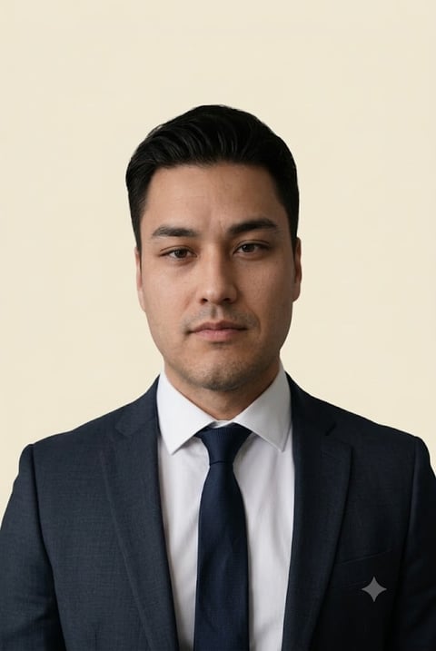 Professional headshot of a man in a dark suit and navy tie against a beige background