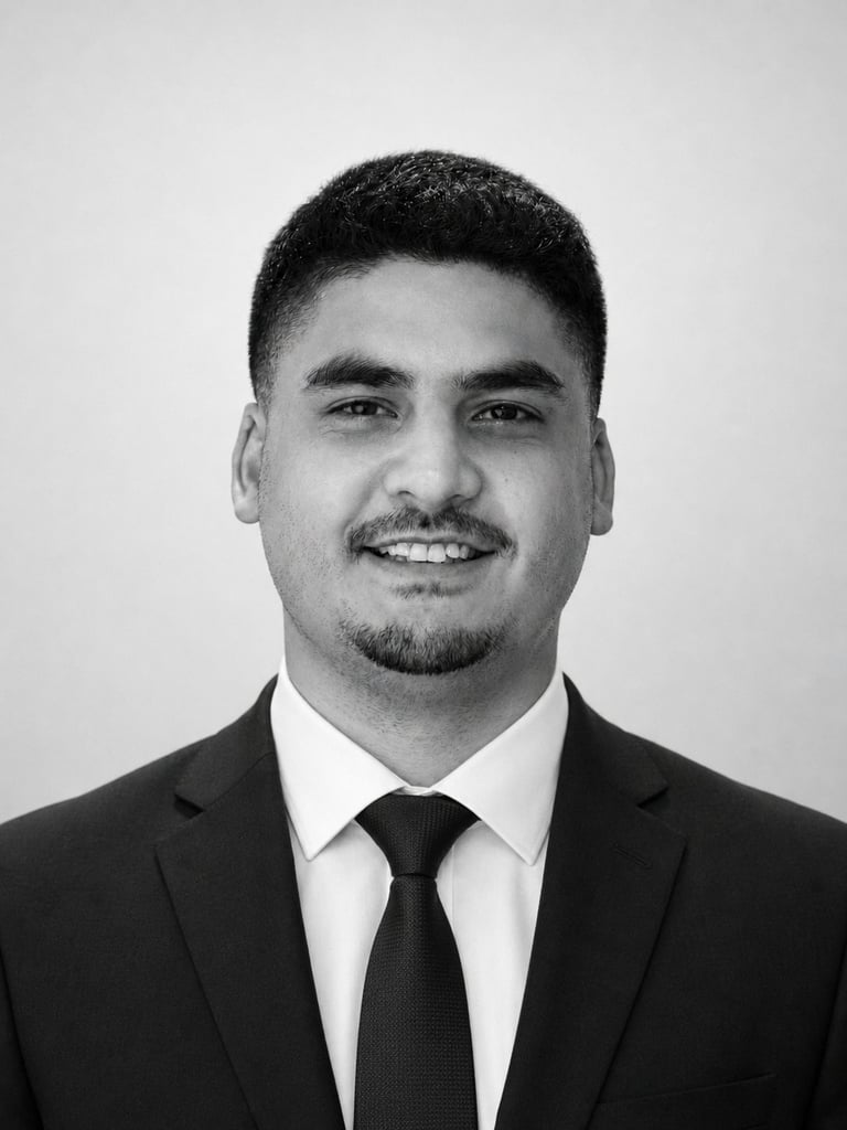 Black and white professional headshot of a man in business suit and tie, smiling at camera against neutral background
